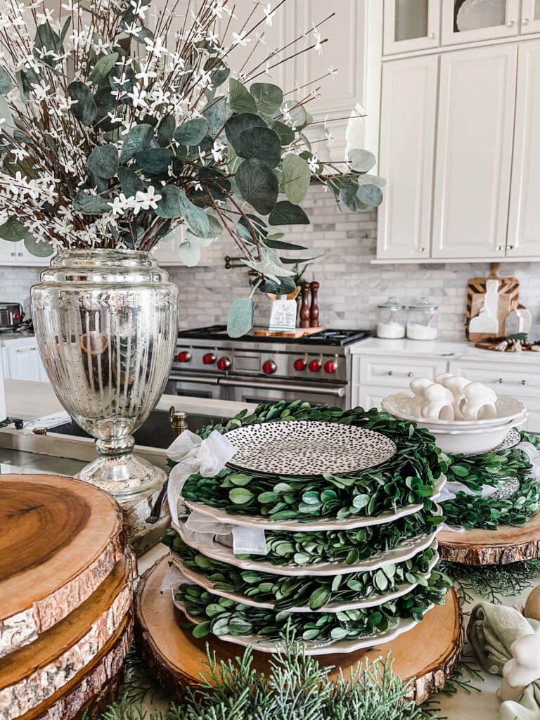 Stacked plates layered with green boxwood wreaths.