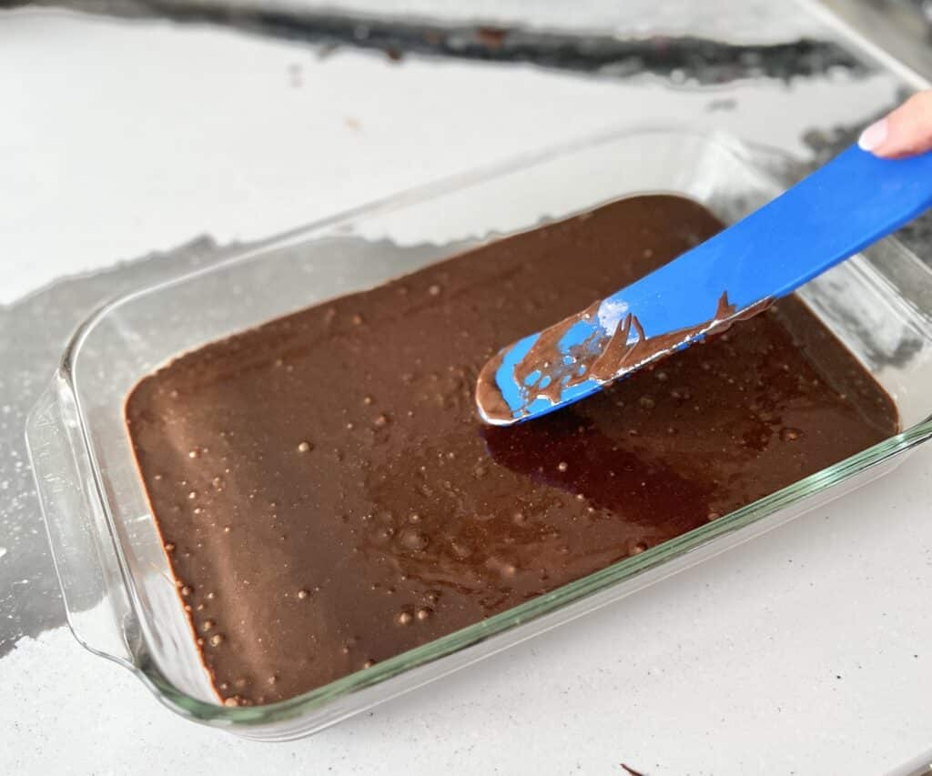 Smoothing the last layer of brownie batter with a spatula.