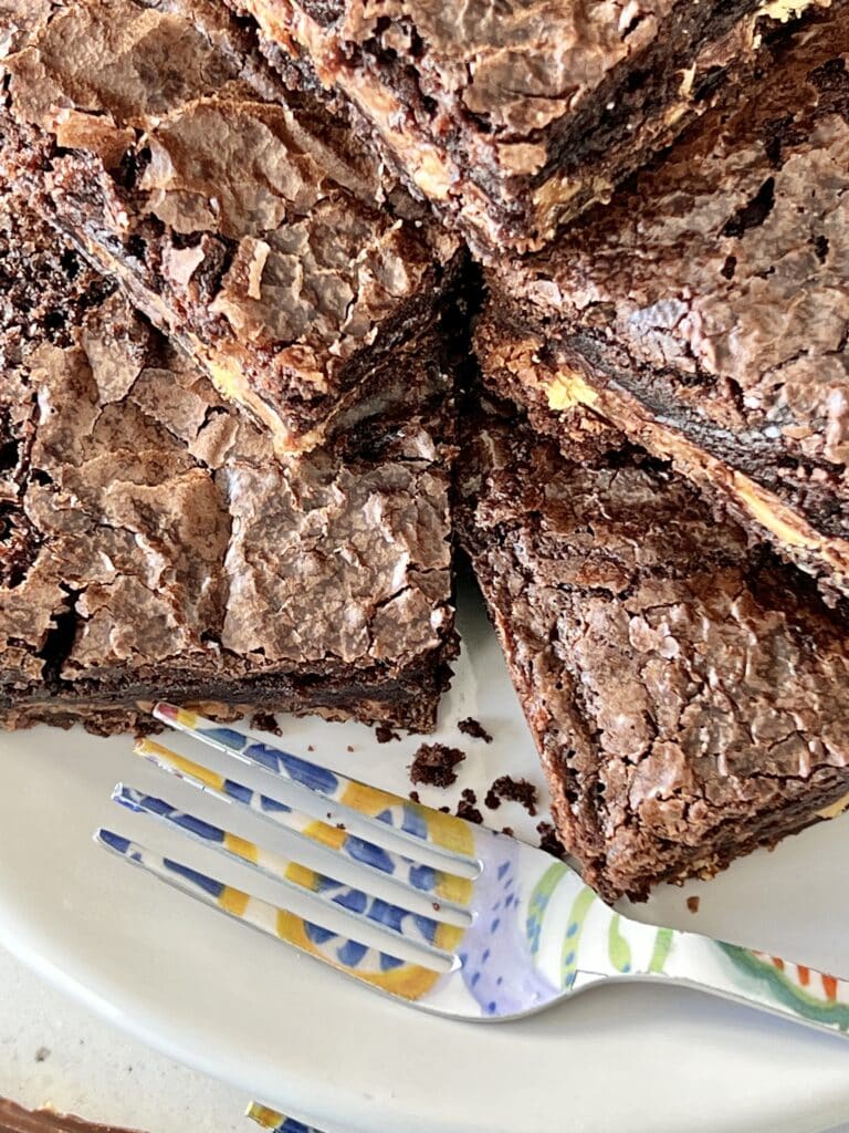 A stack of Symphony brownies on a plate with a colorful fork.