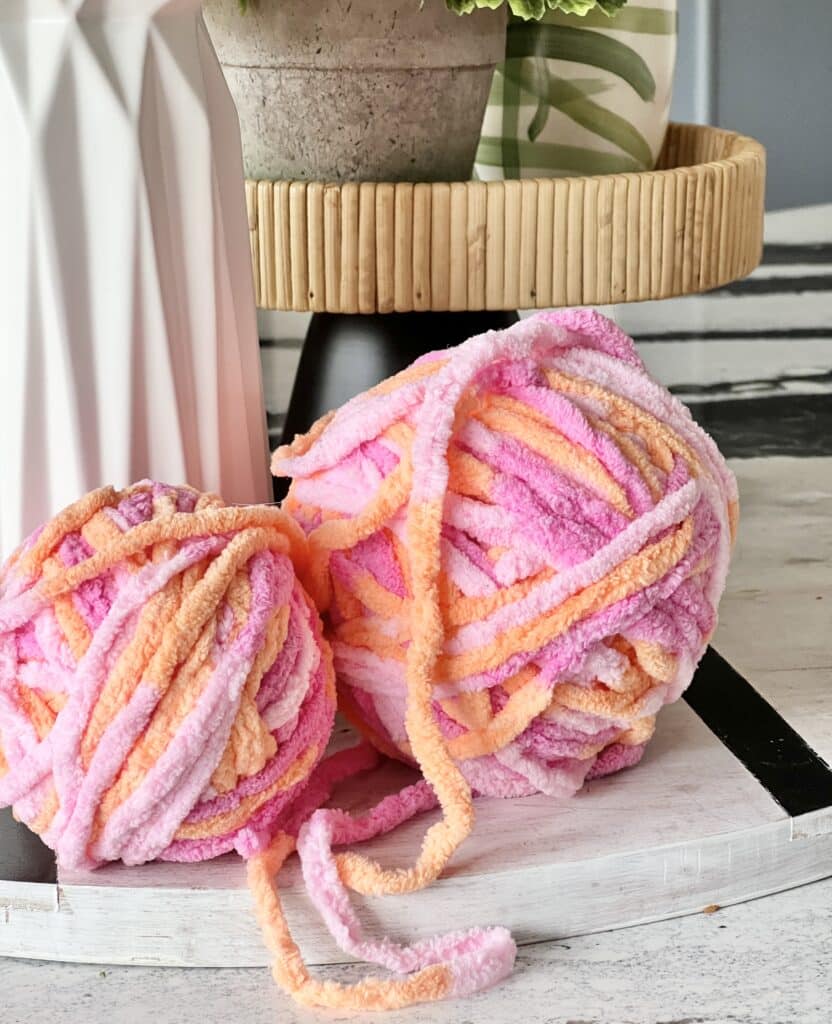 Two balls of pink and peach ombre yarn.