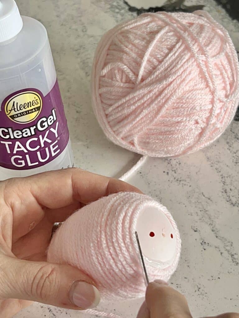 Winding and wrapping  a plastic egg with glue and yarn.