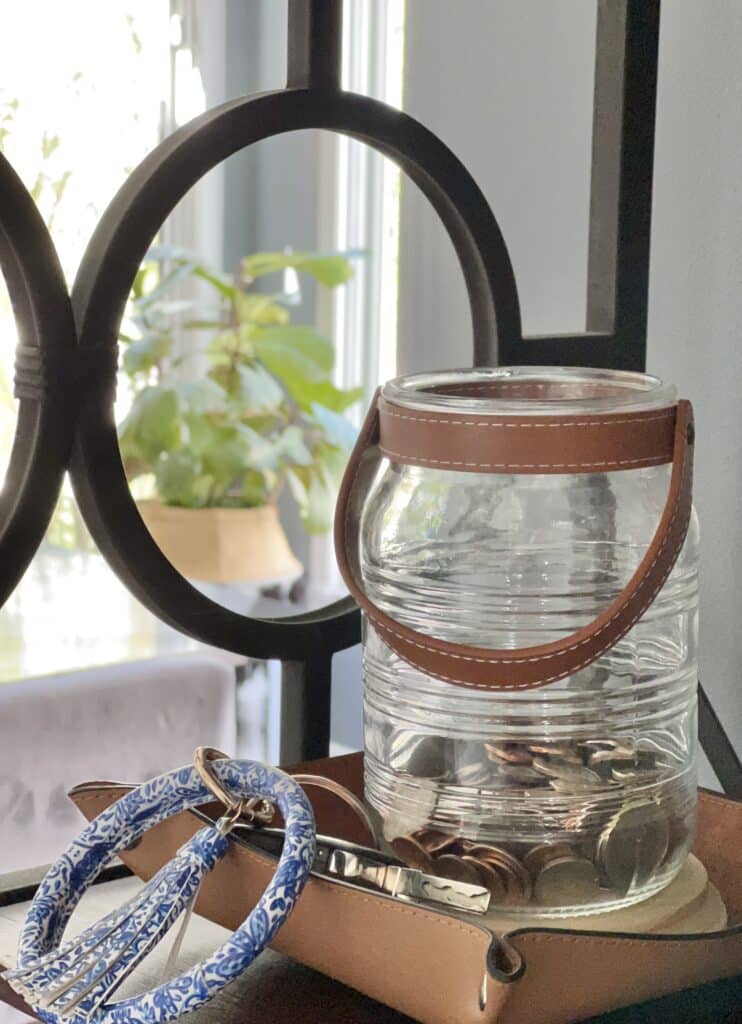 A glass jar with a leather handle is the container for loose change.