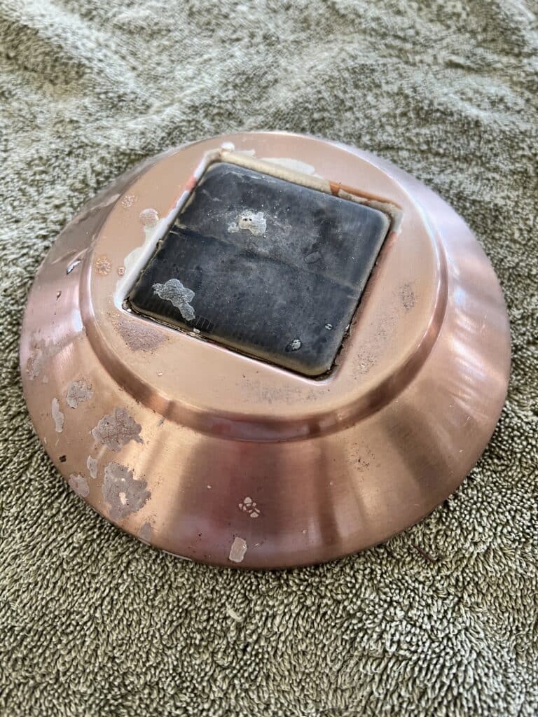 Old solar path light cover with faded copper color and cloudy solar panel.