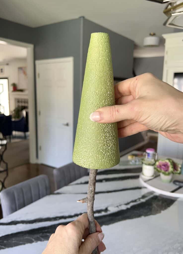 Placing the styrofoam cone on the top of the branch.
