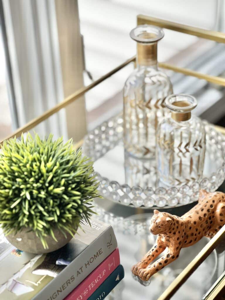 A bar cart accessorized with glass bottles and a thrifted ceramic leopard.