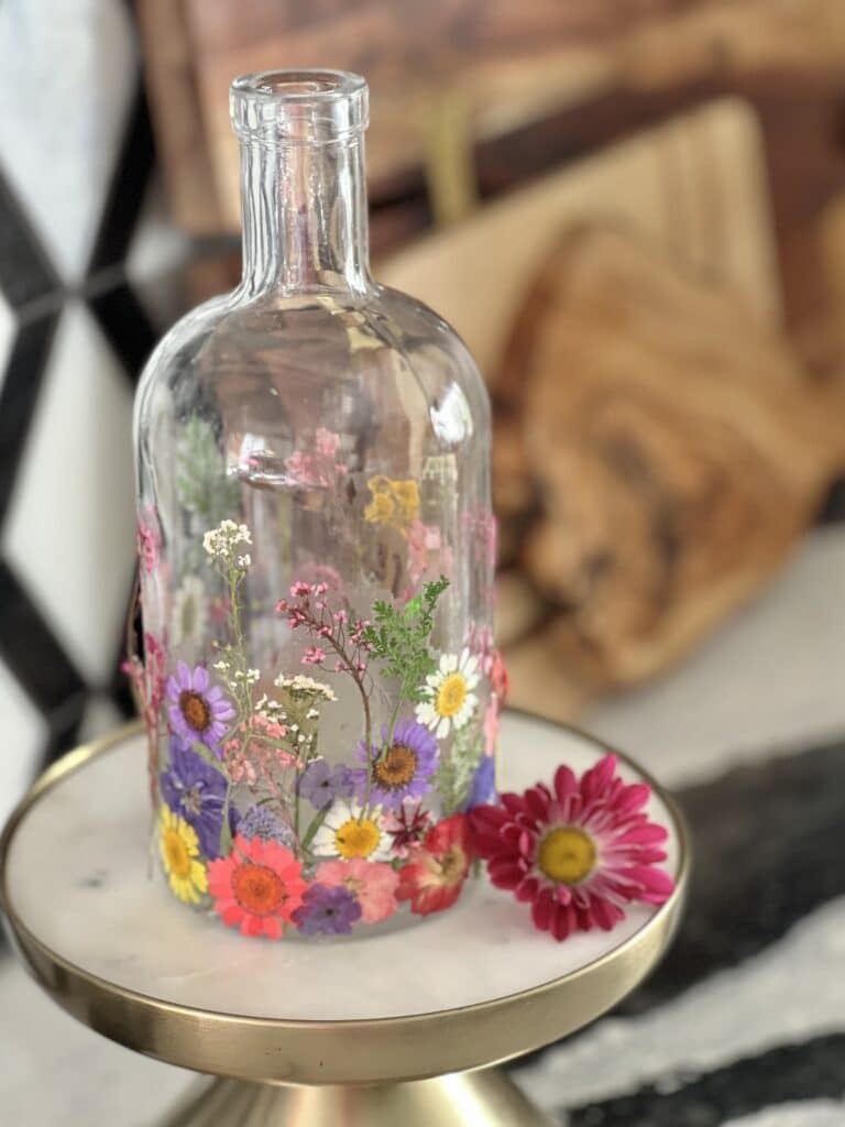 Pressed flower kitchen vase decor sitting in front of wood cutting boards.