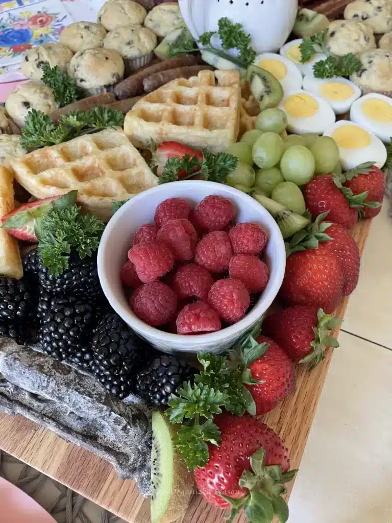 A breakfast board full of fresh fruit and waffles.