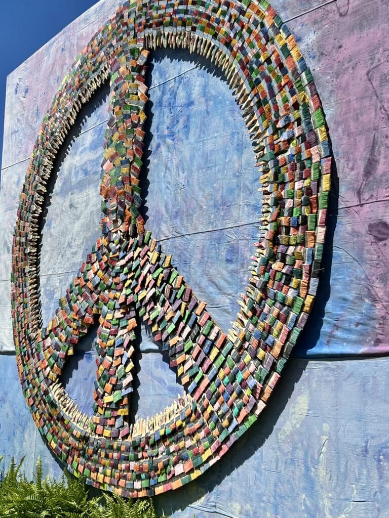A peace sign made entirely of paint brushes.