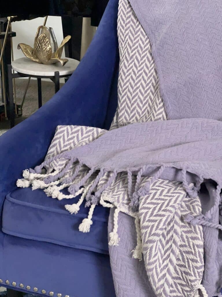 Lavender purple throw blankets on a cobalt blue chair.