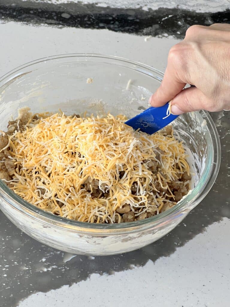 Stirring cheddar cheese into the thick muffin batter.