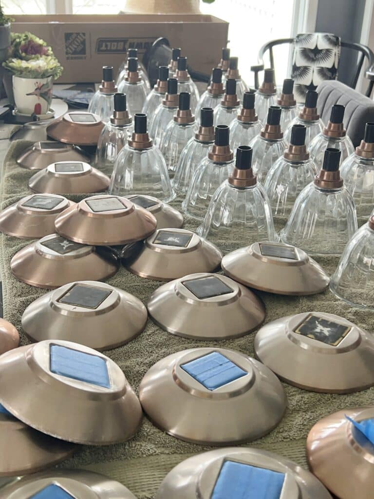 Bunches of glass globes and light covers lined up in an organized assembly line in order to spray paint them.