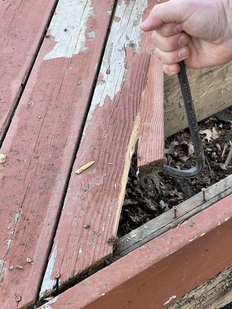 Using a crowbar to lift up boards from the deck.