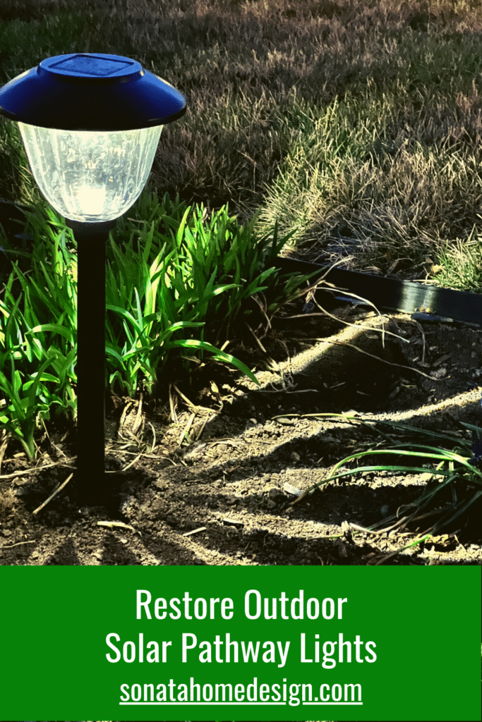 Solar pathway lights that have been refurbished with black paint and lines the outer edges of a patio.