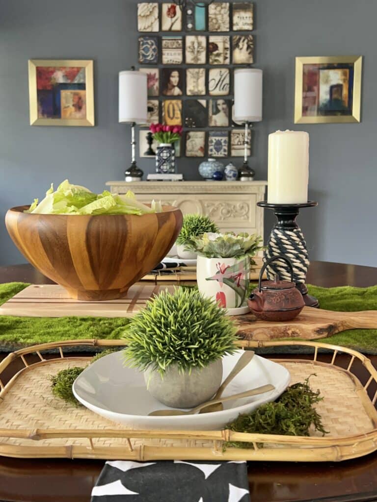 A green moss table runner with green inspired decor items placed on top.
