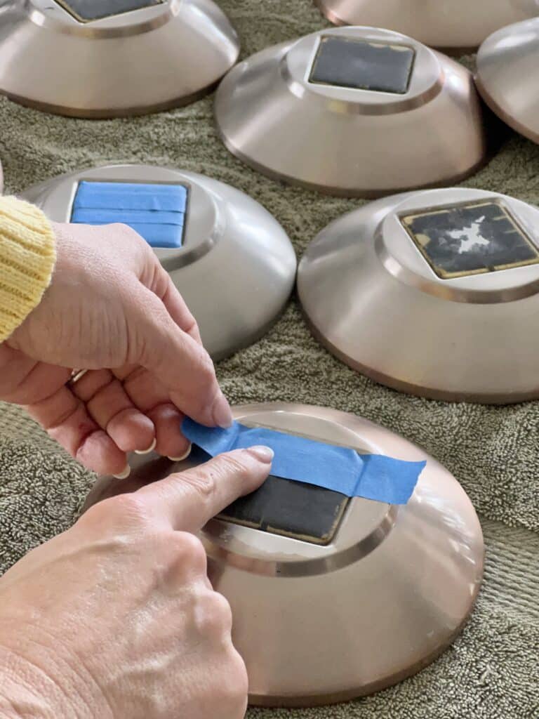 Taping off the solar panel of a light cap with painter's tape.