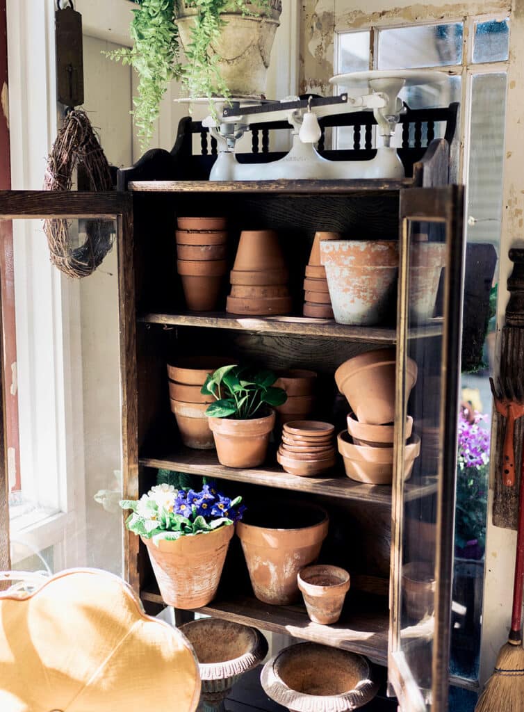 A wood hutch holding terra cotta pots of various sizes.