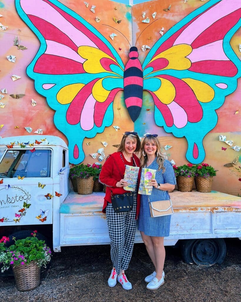 Missy and Madeline standing in front of a colorful wood butterfly at Junkstock.