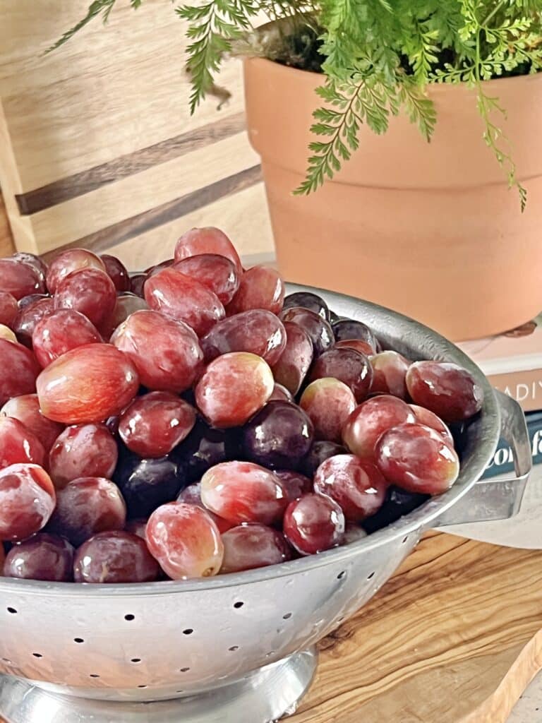 A colander full of freshly washed red seedless grapes.