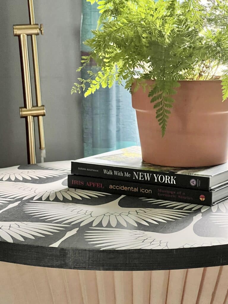 Books and a fern sitting on top of a diy side table made from fabric lampshades.