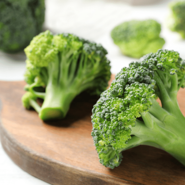 Cut broccoli on a wood cutting board.