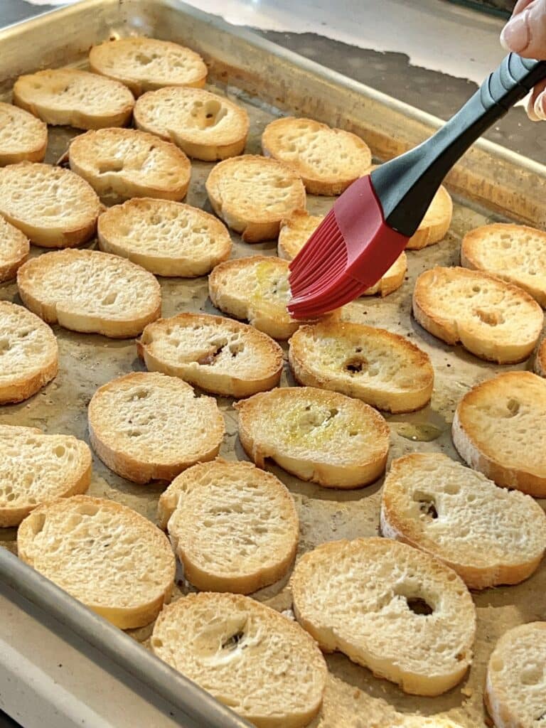 Brushing the toasted bread slices with olive oil.