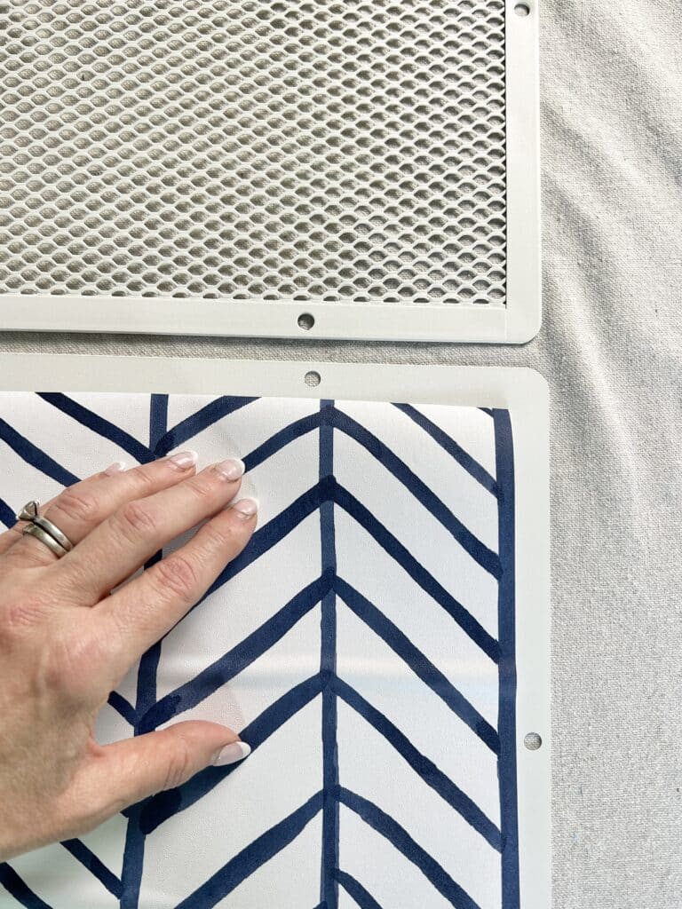 Applying a cut piece of wallpaper on one of the Ikea cart shelves.