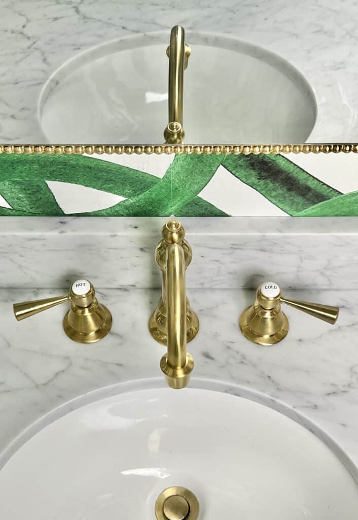 The gold faucet reflected in the half bathroom mirror.