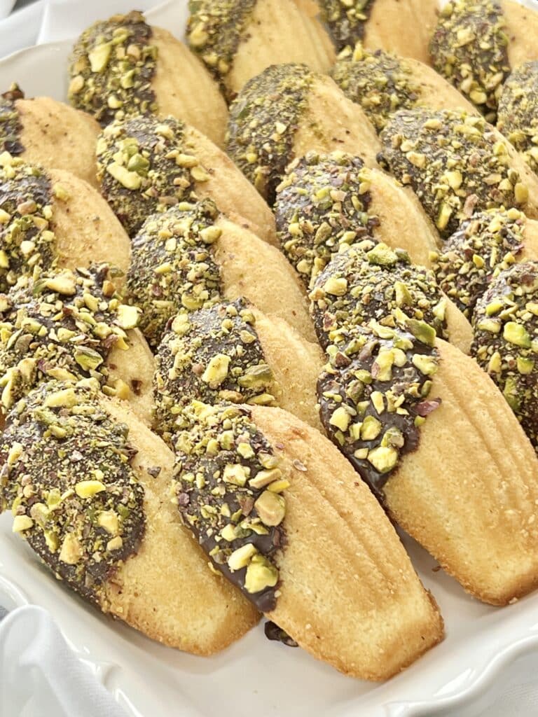 Madeleine cookies dipped in chocolate and chopped pistachio nuts.