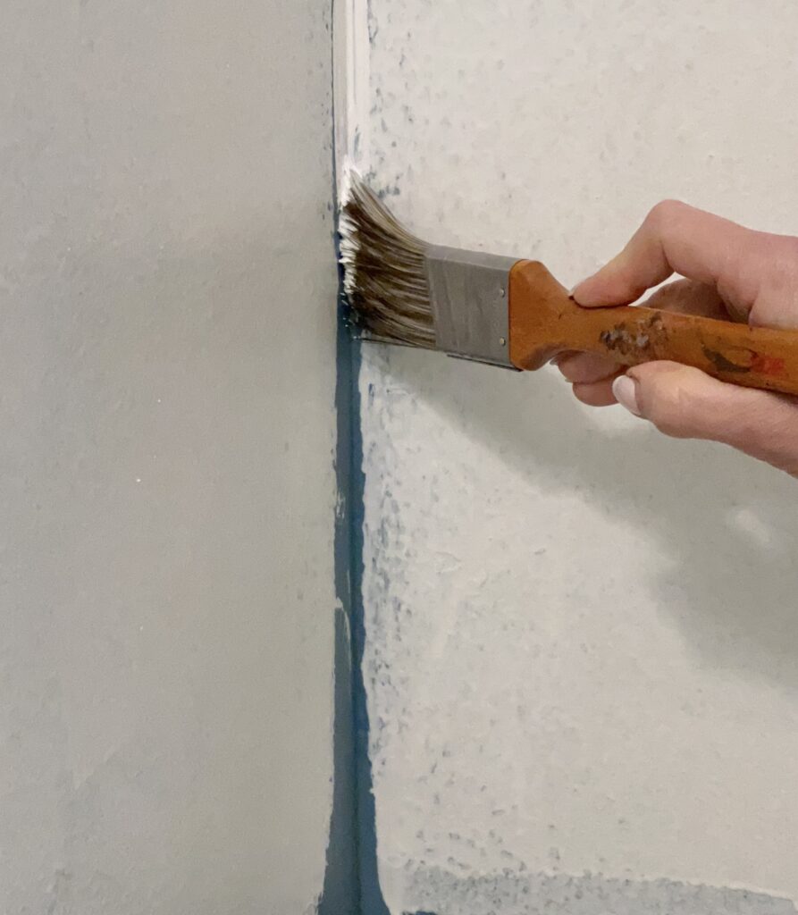 Using a paint brush to apply the best paint primer for dark walls in the corners.
