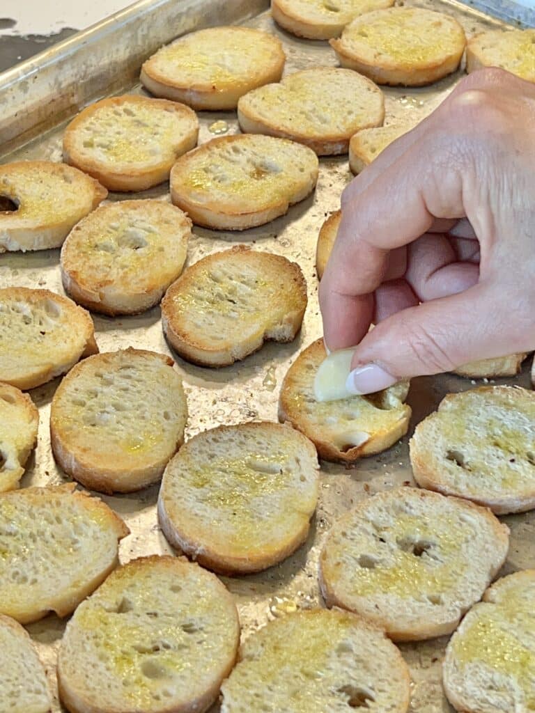 Rubbing each of the toasts with a clove of garlic.