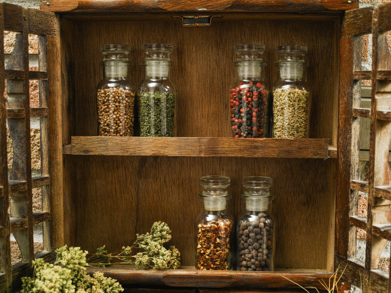 Bottles of spices sitting on the shelves of a wood hutch.