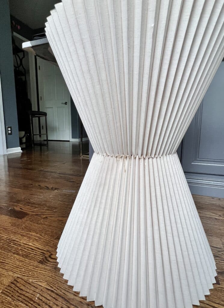 A pleated lampshade inverted and glued on top of another pleated lampshade to create a table base.
