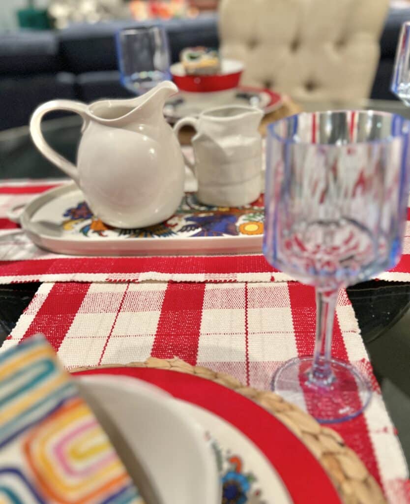 Two red and cream plaid table runner intersecting in the middle of a round dining room table.