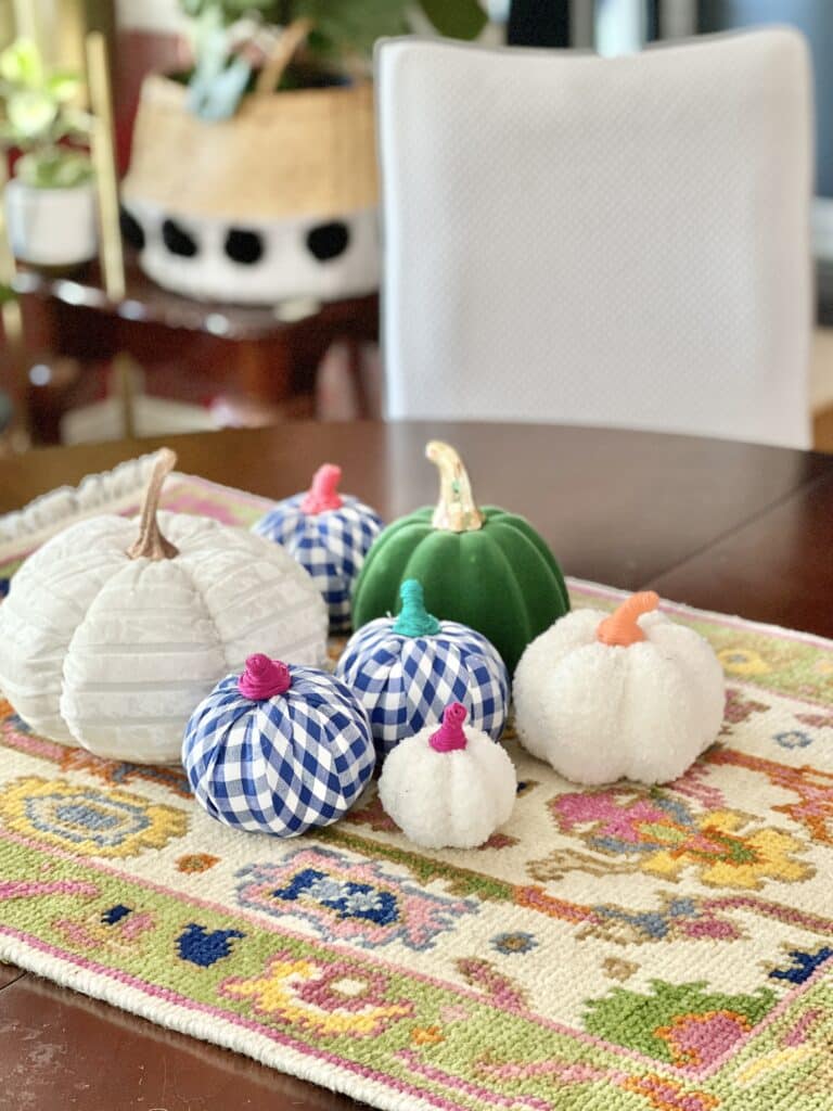 everyday table centerpiece ideas: Petite pumpkins laying on a small rug on a dinner table.