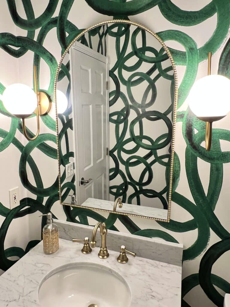 This tiny half bath is full of bold ideas that create a feeling of energy in the room through wallpaper patterns that are large and curving.
