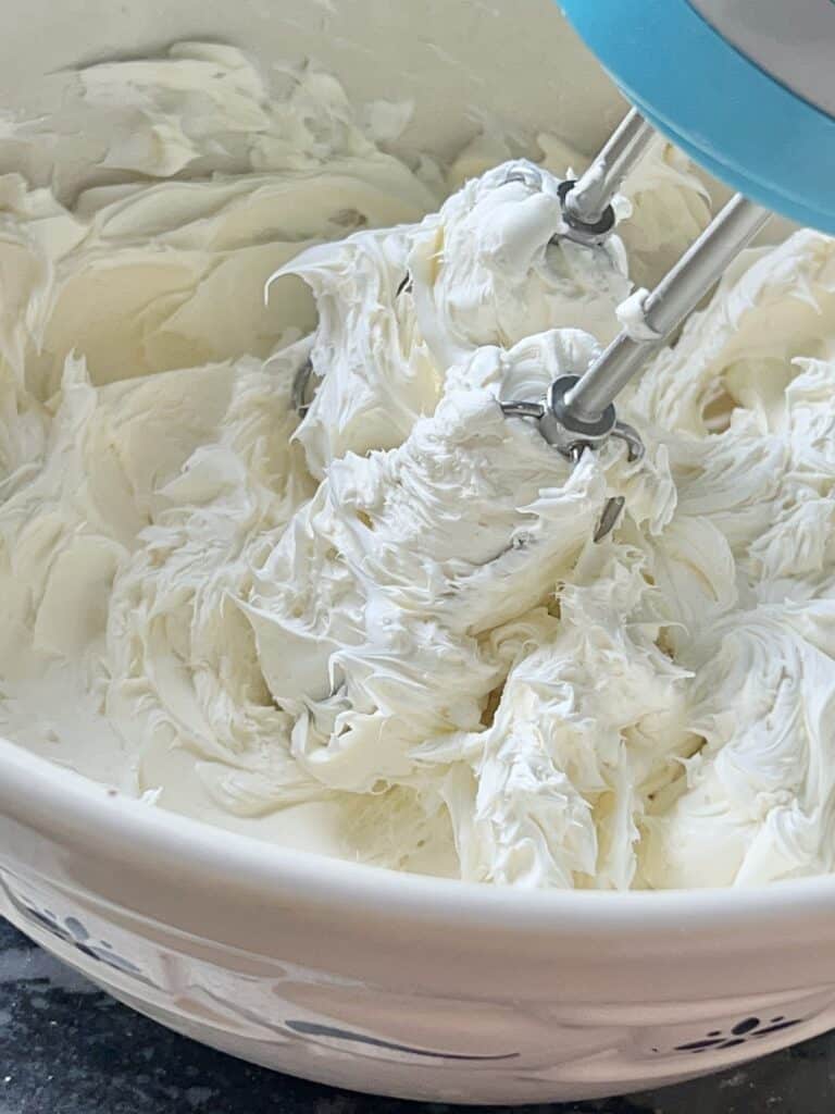 Whipping cream cheese with a hand mixer.