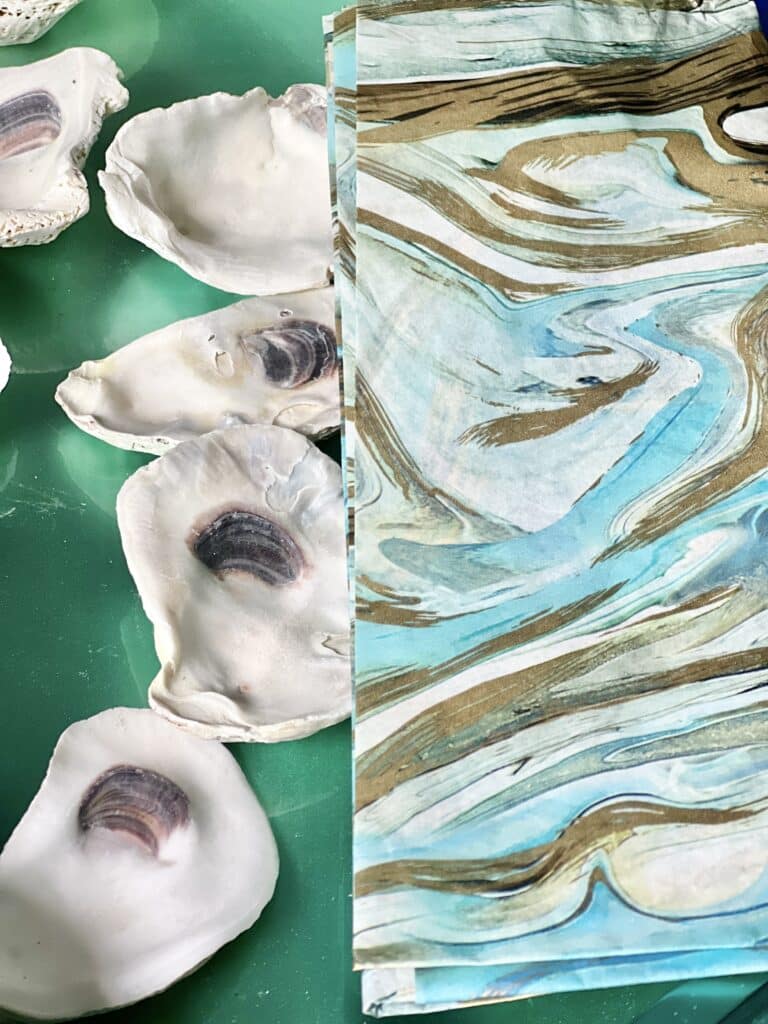 Oyster shells next to tissue paper in a pattern of abstract blues.