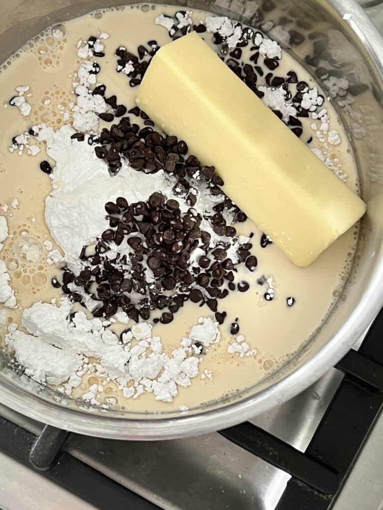 Ingredients for the chocolate sauce in a saucepan on a stovetop.