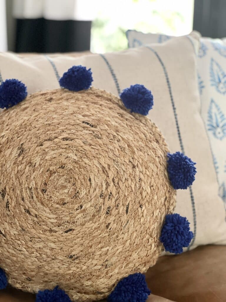 A jute placemat pillow made with DIY pom poms.