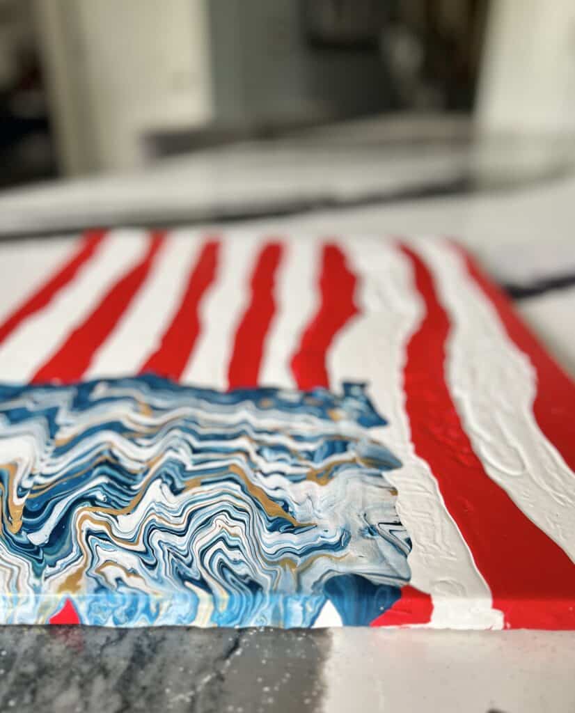 A view of the completed DIY abstract patriotic wall art laying on a kitchen island as it dries.