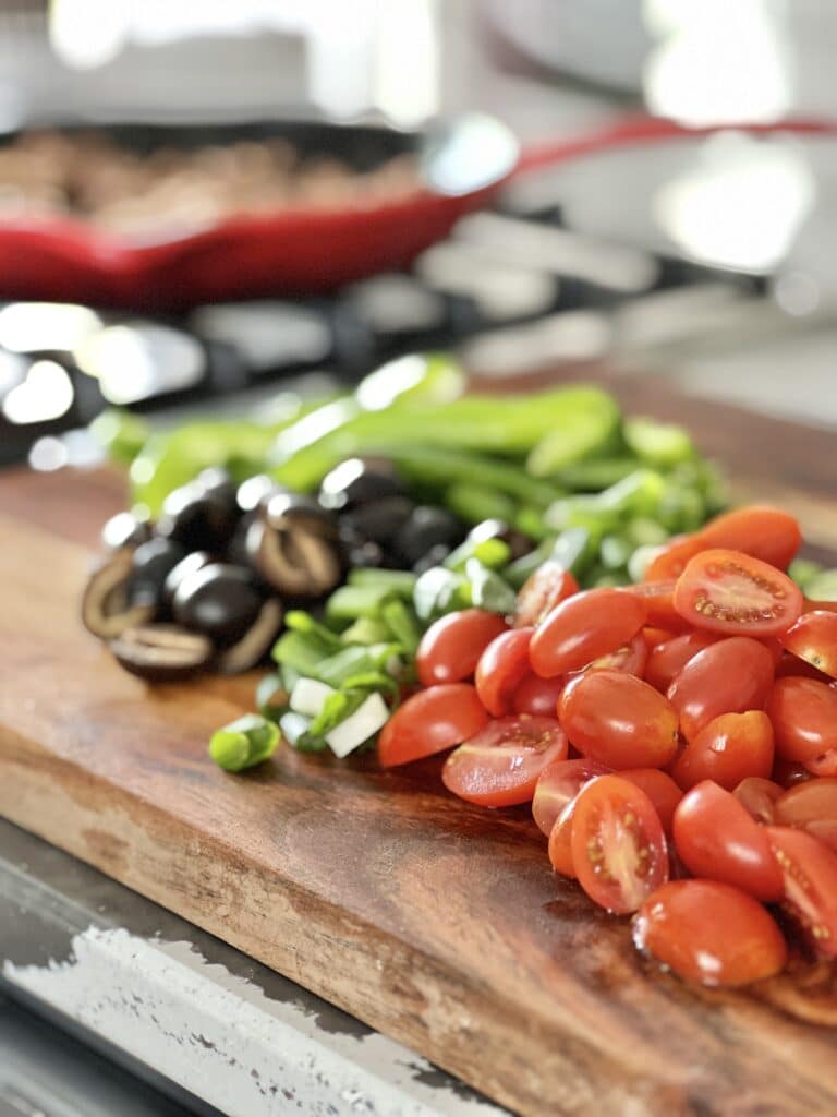 A wood cutting board full of fresh vegetables that have been chopped for healthy Mexican salad recipes.