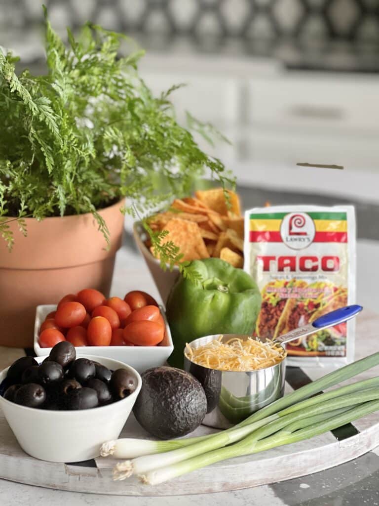 Ingredients for healthy Mexican salad recipes that include tomatoes, avocados, green onions, black olives, and taco seasoning.