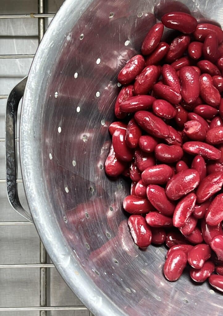 A metal colander full of kidney beans that are draining.