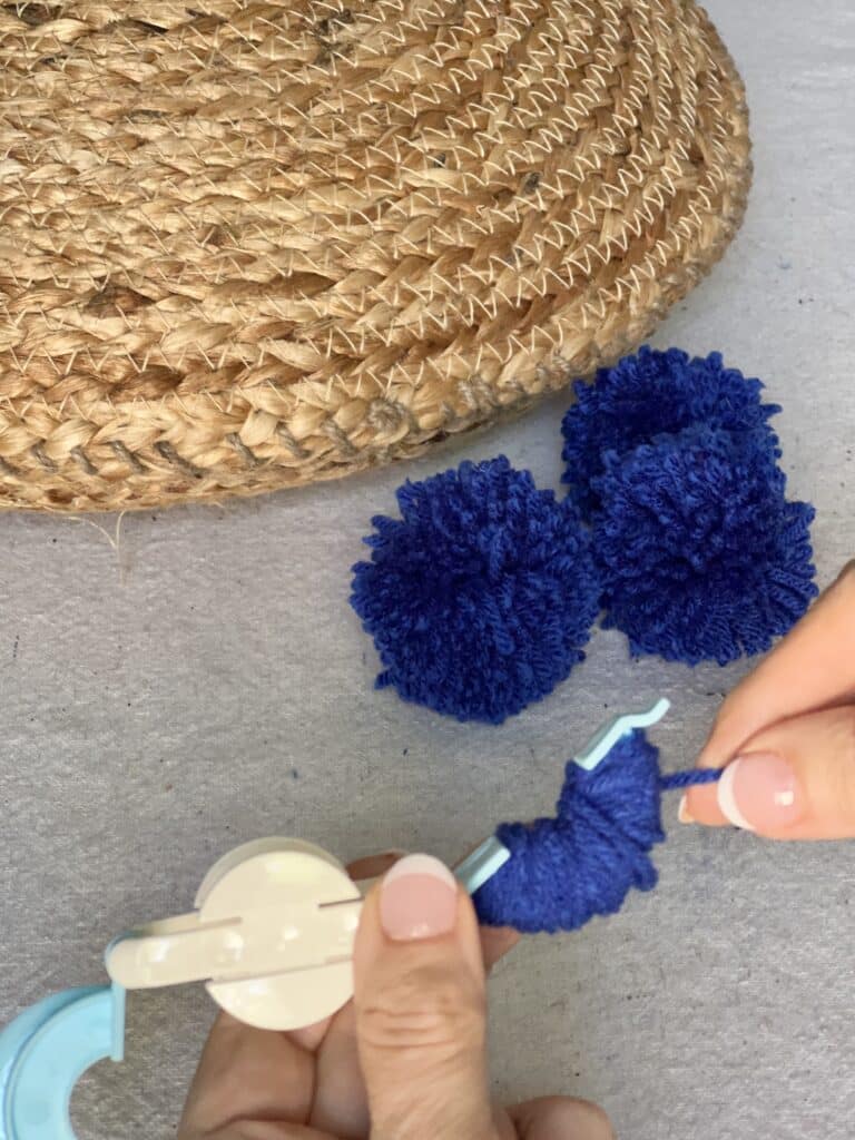 Making pom poms with navy blue yarn for the jute placemat DIY pillow.