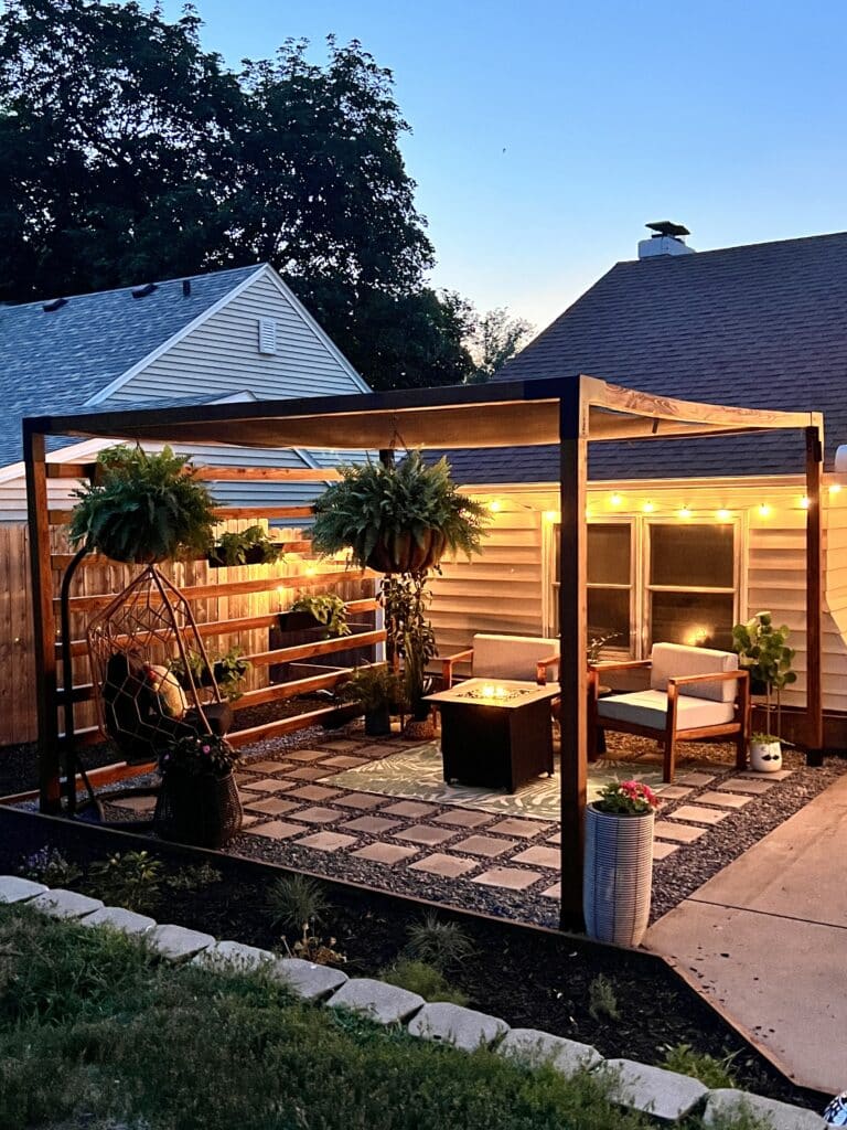 The Toja Grid DIY pergola kit illuminated at night with string lights.