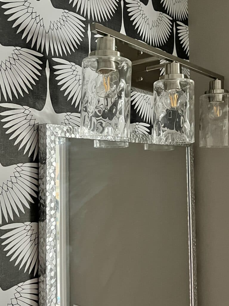 An overhead vanity light hanging above a mirror in a powder room.