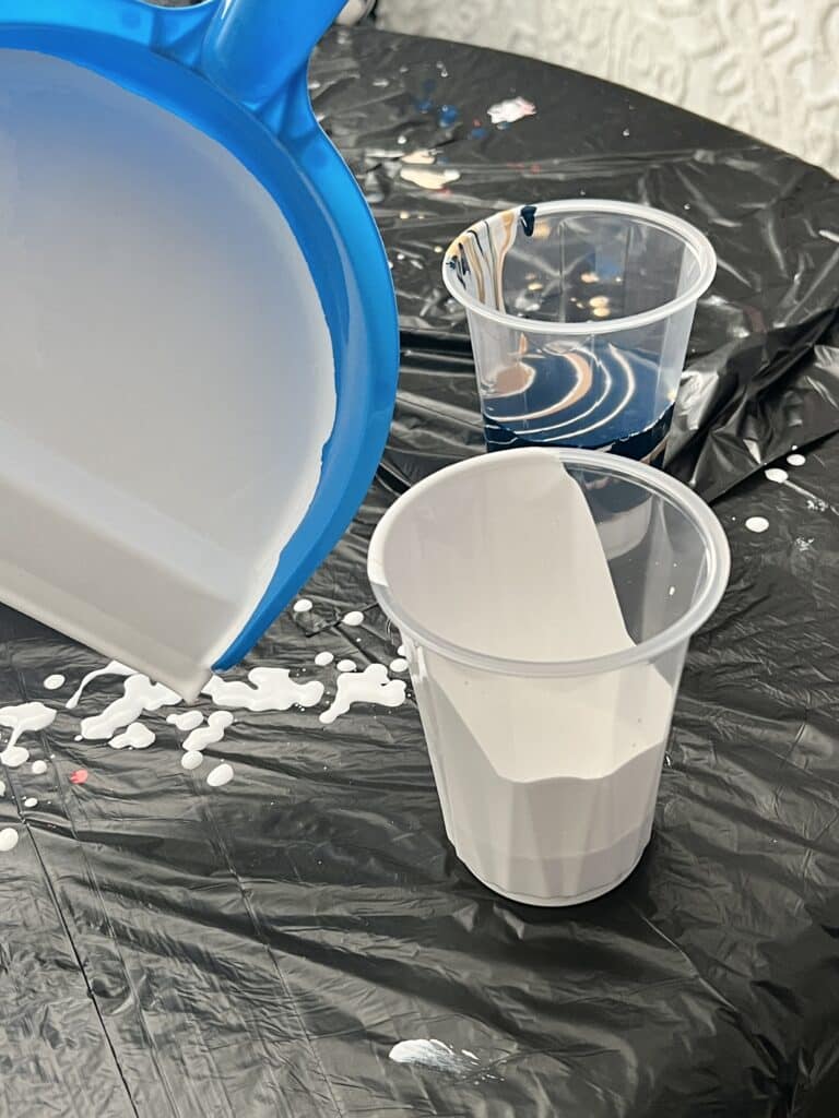 Covering the inside of a dustpan with white paint.