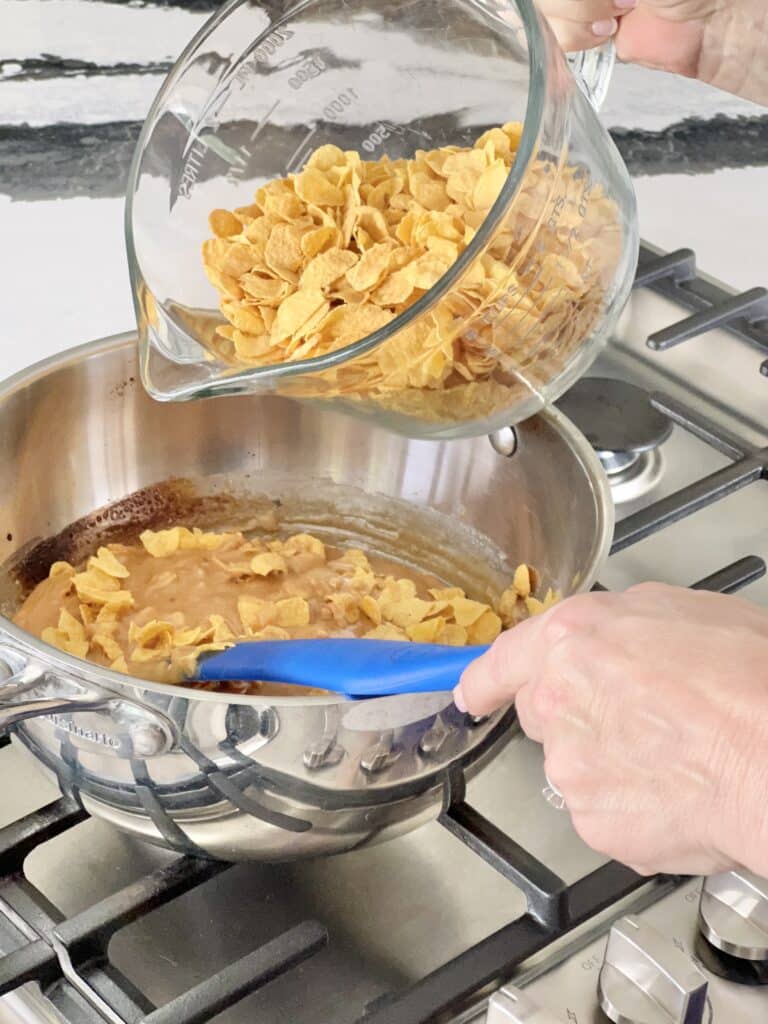 cereal cookie recipes: Pouring cornflakes into a sweet peanut butter mixture.