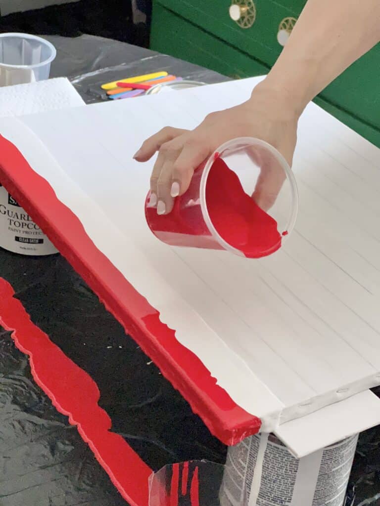 Pouring the third red stripe on the DIY abstract flag wall art.