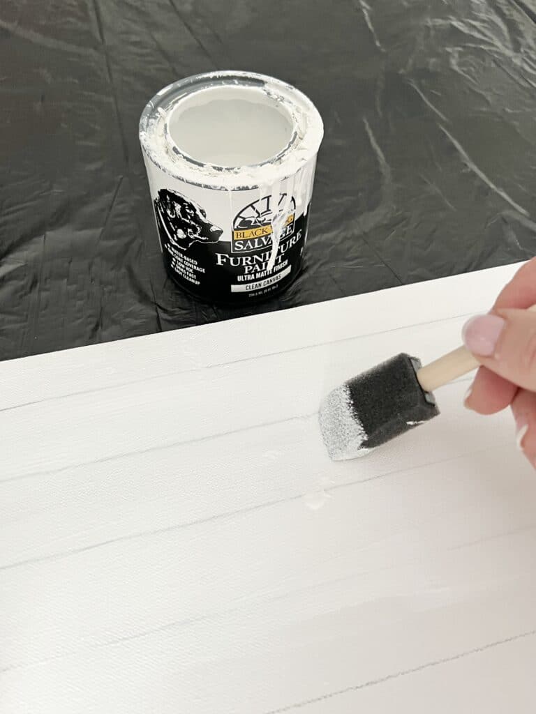 Painting a canvas white in preparation for the paint pour.